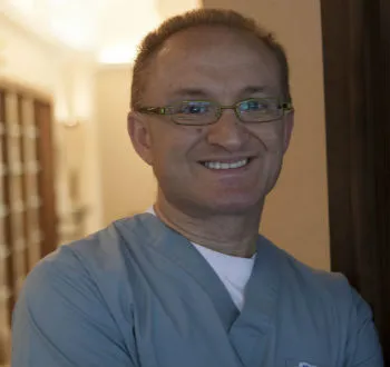 Reza2 A man in a scrub suit smiling at the camera.